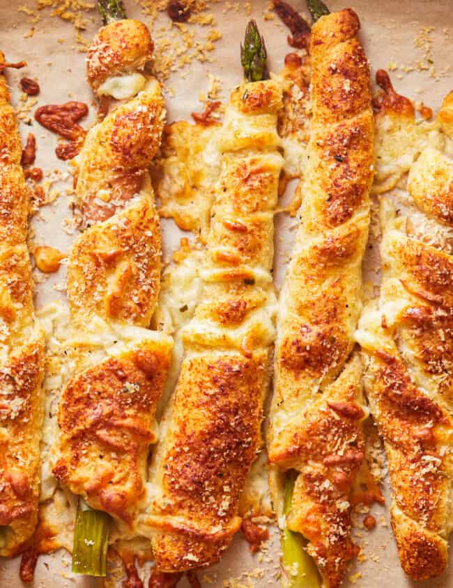 overhead view of asparagus crescent rolls pointing north-south on parchment paper.