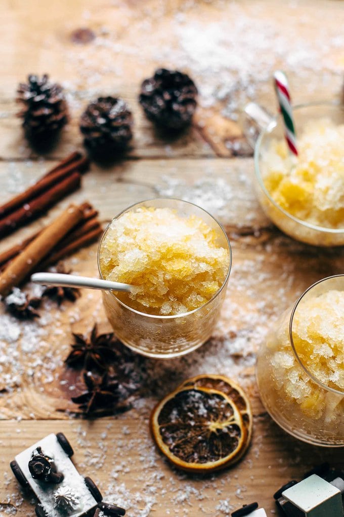 Glasses filled with orange bourbon slush, with cinnamon sticks scattered around