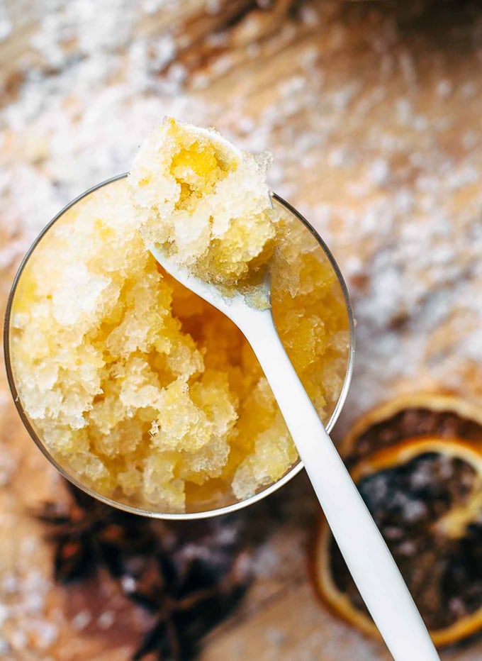 Orange slush on a spoon, sitting on top of a glass