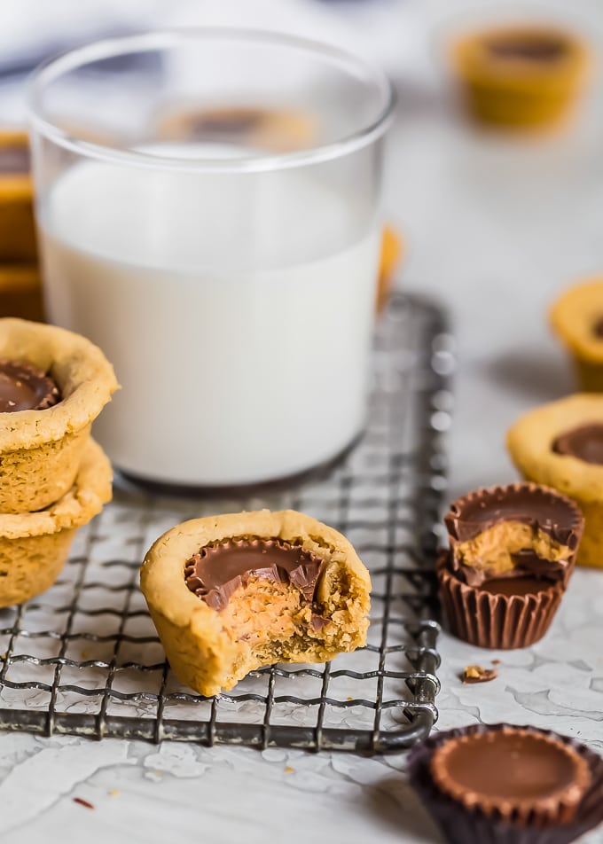 a glass of milk surrounded by peanut butter cups and cookies