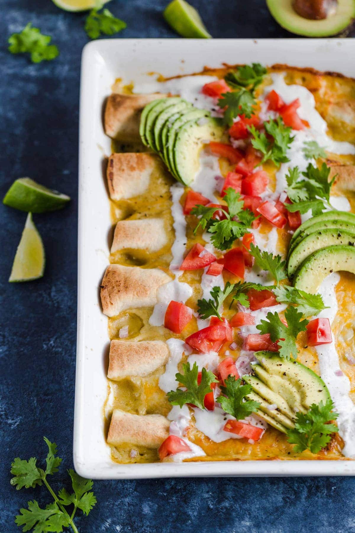 Honey Lime Chicken Enchiladas topped with tomatoes, avocado, sour cream, and cilantro