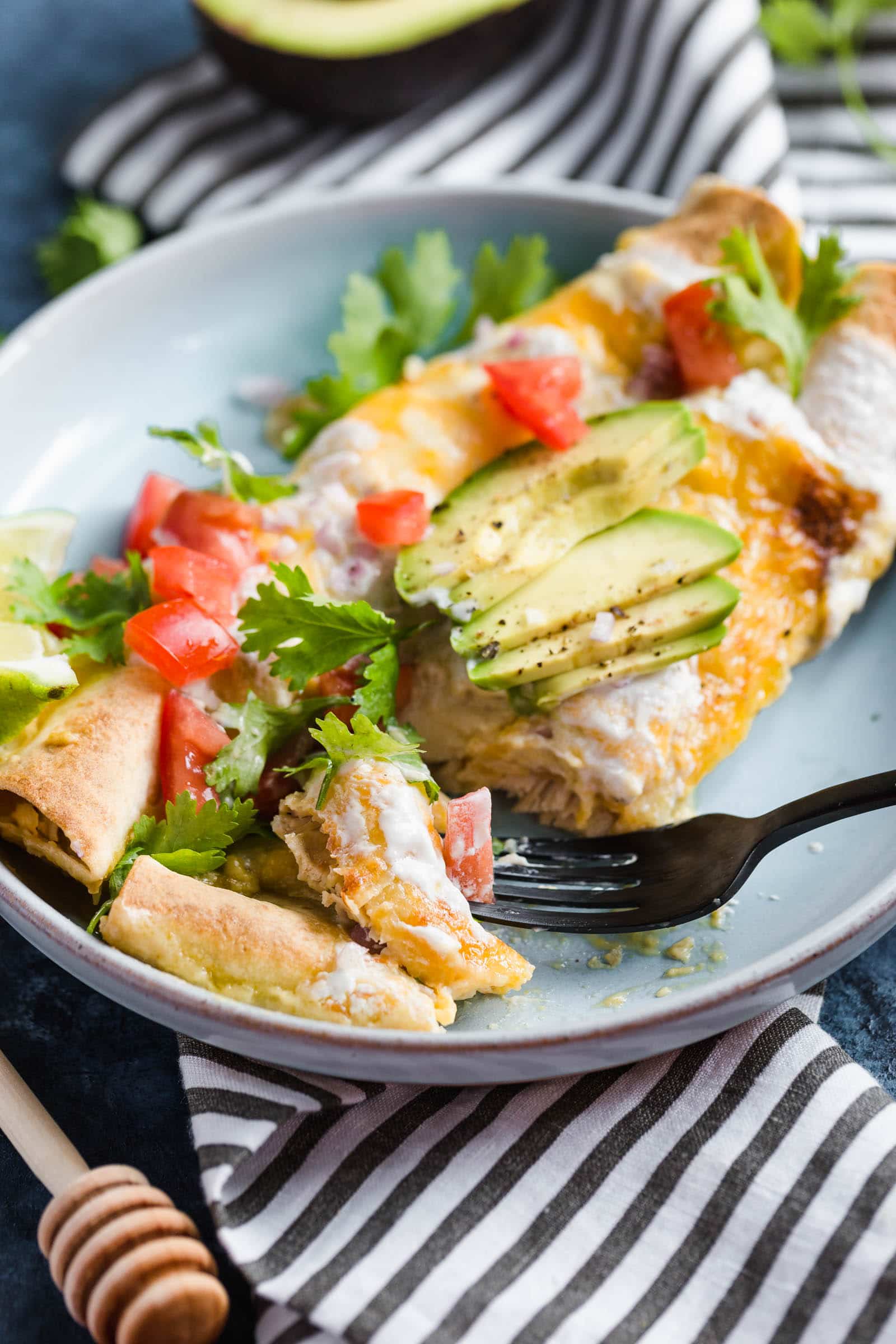 A plate of enchiladas topped with cheese and sour cream