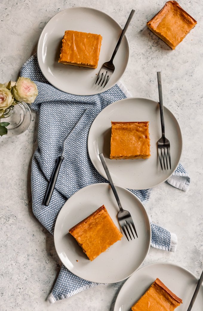 Three white plates with pumpkin gooey butter cake bars