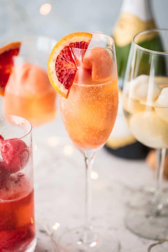 tall stemmed glass holding a fruity mimosa cocktail with orange sherbet