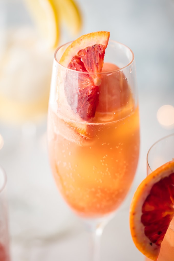 close up image of an orange sherbet mimosa cocktail garnished with a slice of blood orange