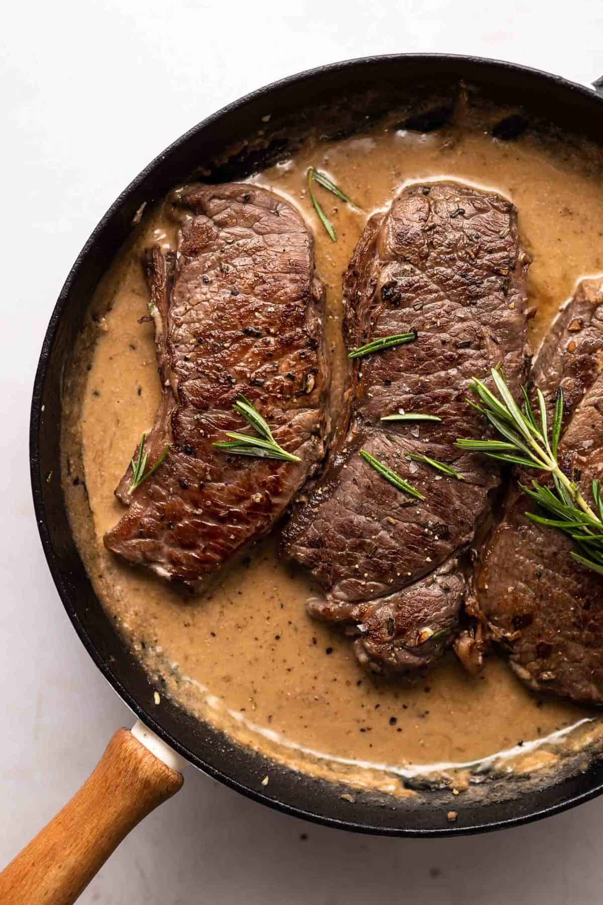 steak in a skillet with sherry cream sauce.