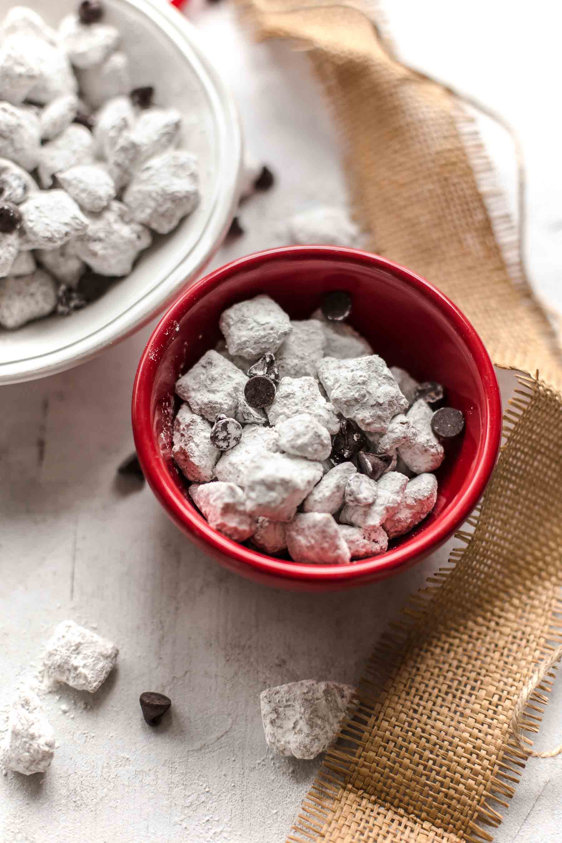 small red bowl of puppy chow next to a larger white bowl