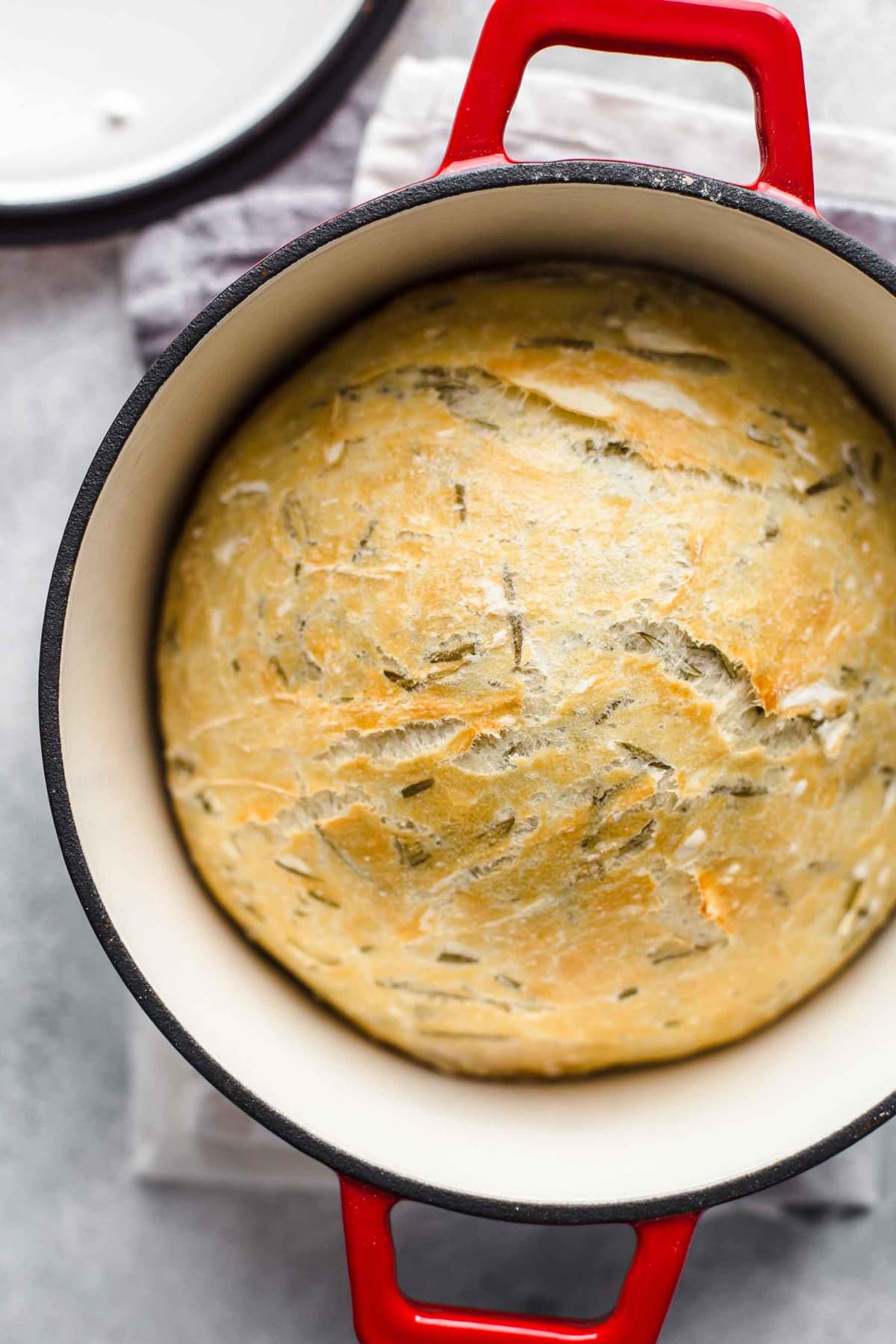 a loaf of bread in a red dutch oven.