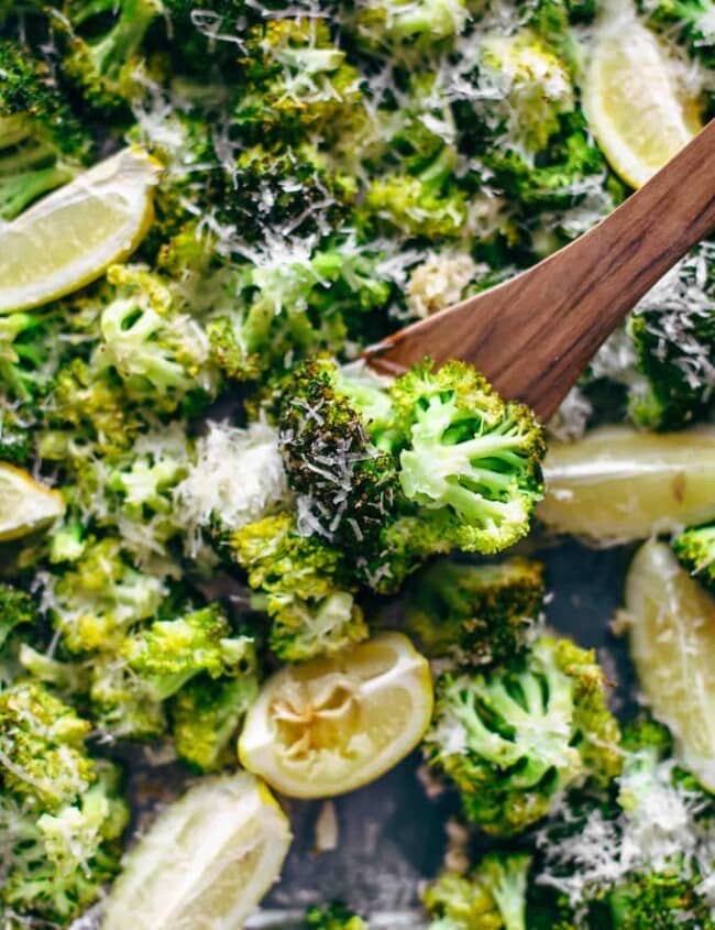 broccoli on a baking dish with lemon wedges and parmesan