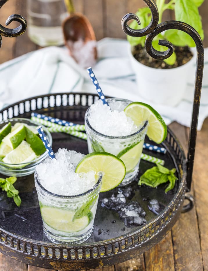 mojitos on a tray with sliced lime wedges in a bowl