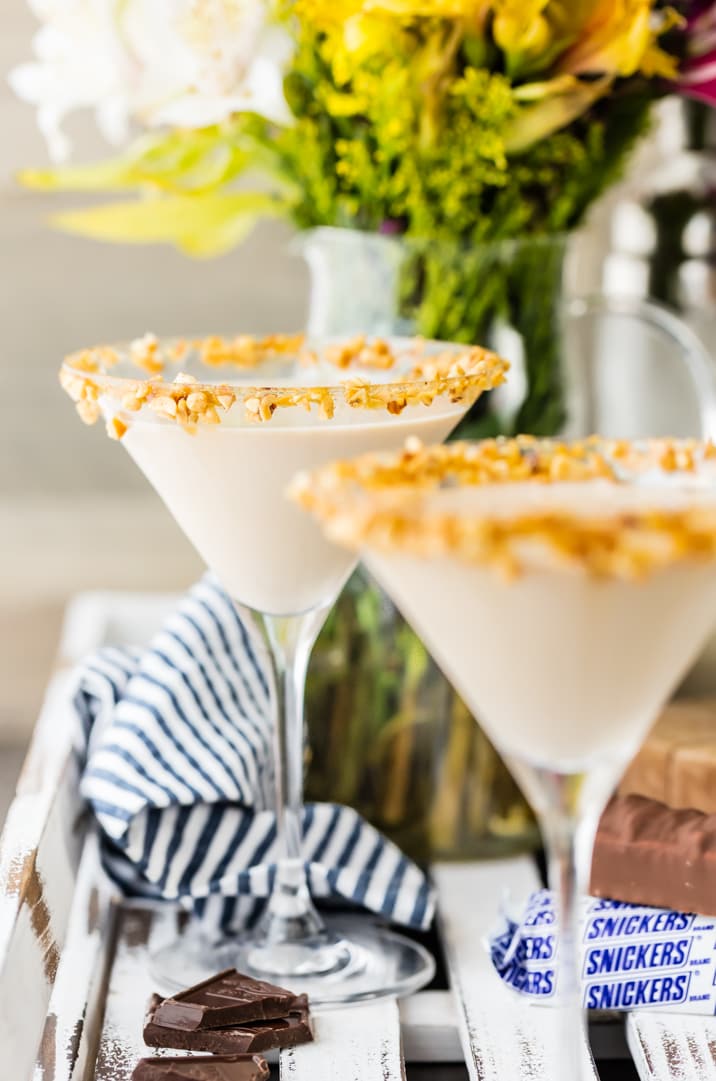 A table topped with a cut in half on a plate, with Martini and Snickers