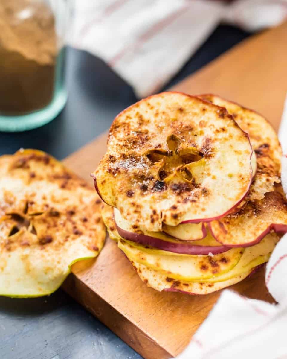 A stack of apple slices on a cutting board, transformed into microwave apple chips.