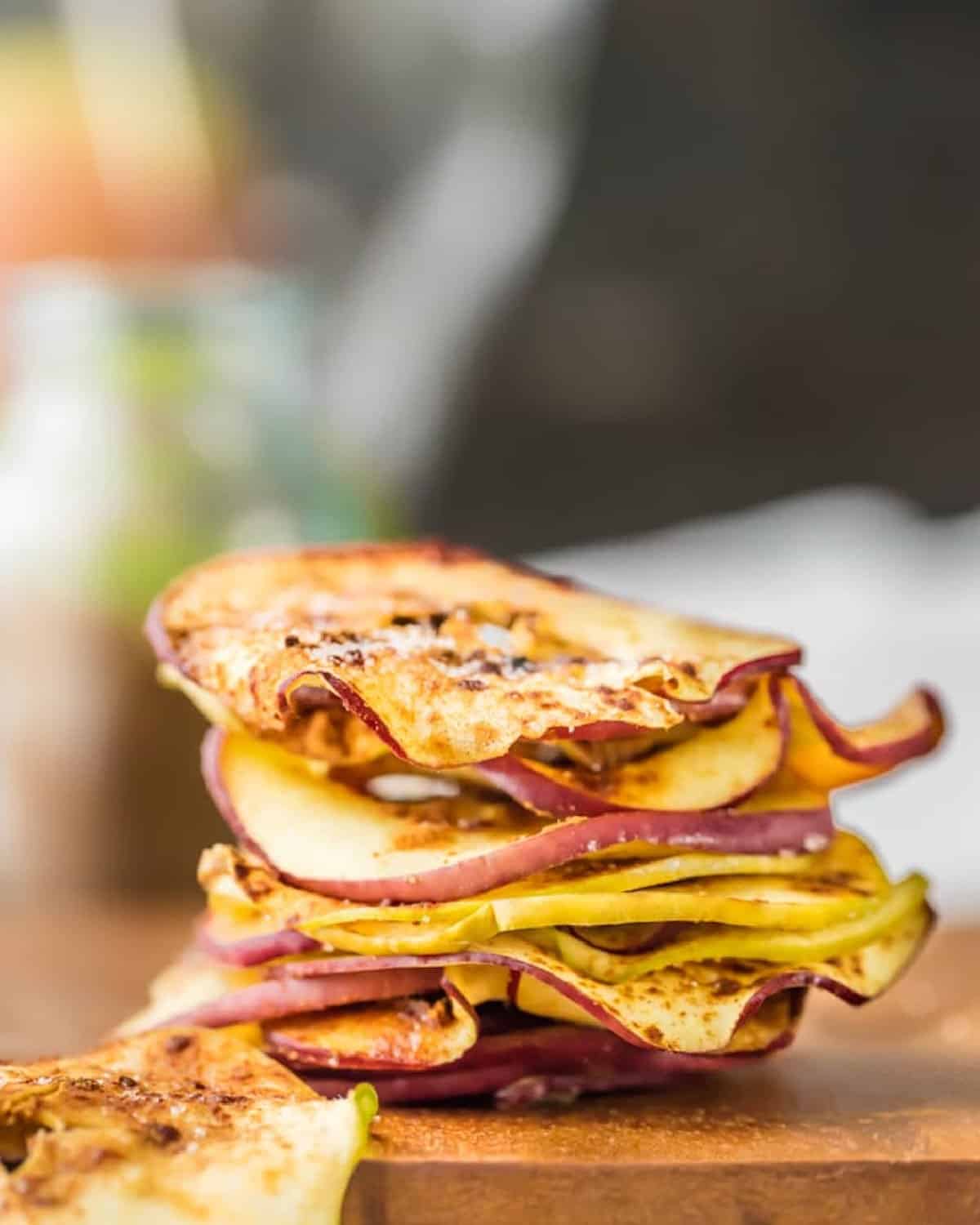 A stack of apple slices on a cutting board for making microwave apple chips.