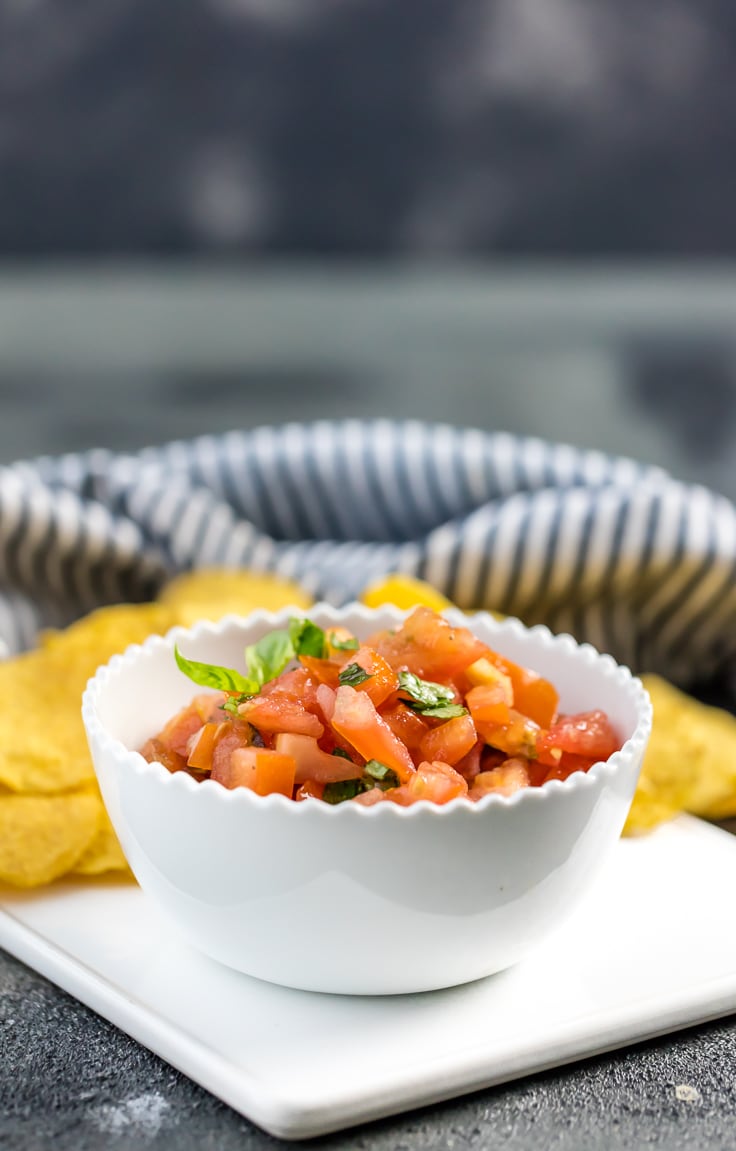 Italian salsa in white bowl with striped towel in background.