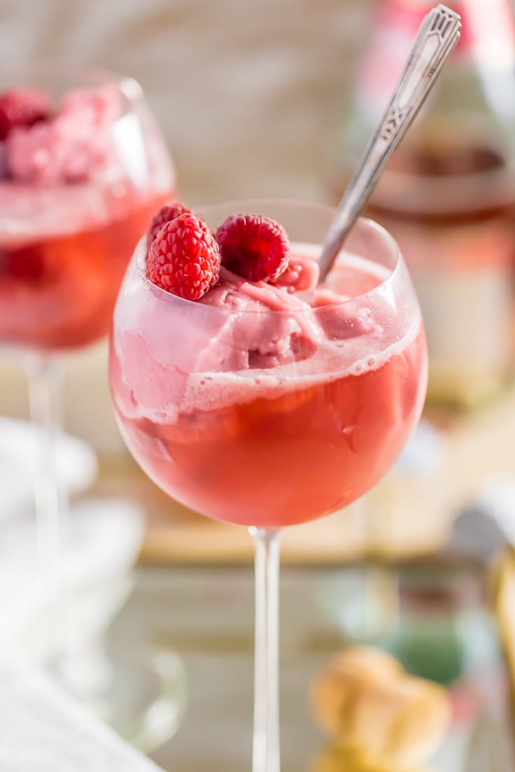 close up on a wine glass filled with raspberry sorbet and pink champagne, with a silver spoon stuck in it