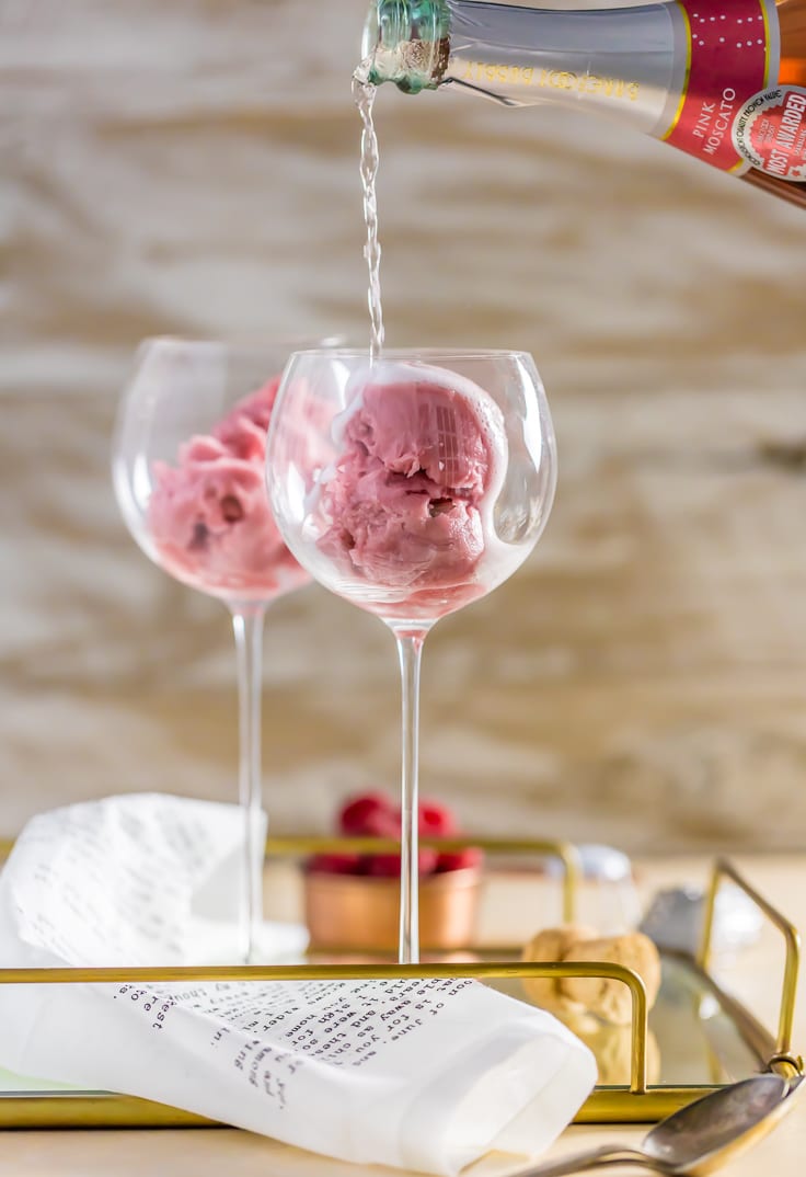 pouring pink champagne into a glass filled with raspberry sorbet