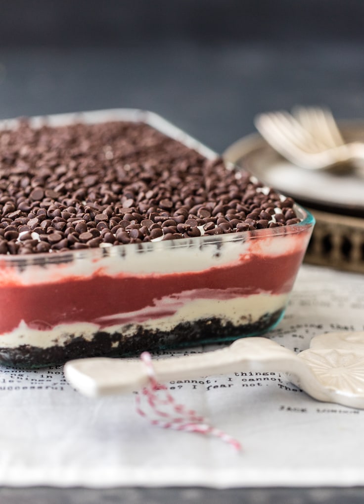 Layers of whipped cream, cheesecake, chocolate pudding, oreos, and more in a glass baking dish