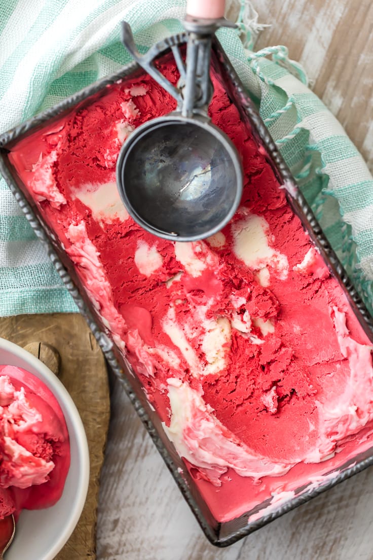 red velvet cream cheese ice cream in a metal pan, with an ice cream scoop laying on top.