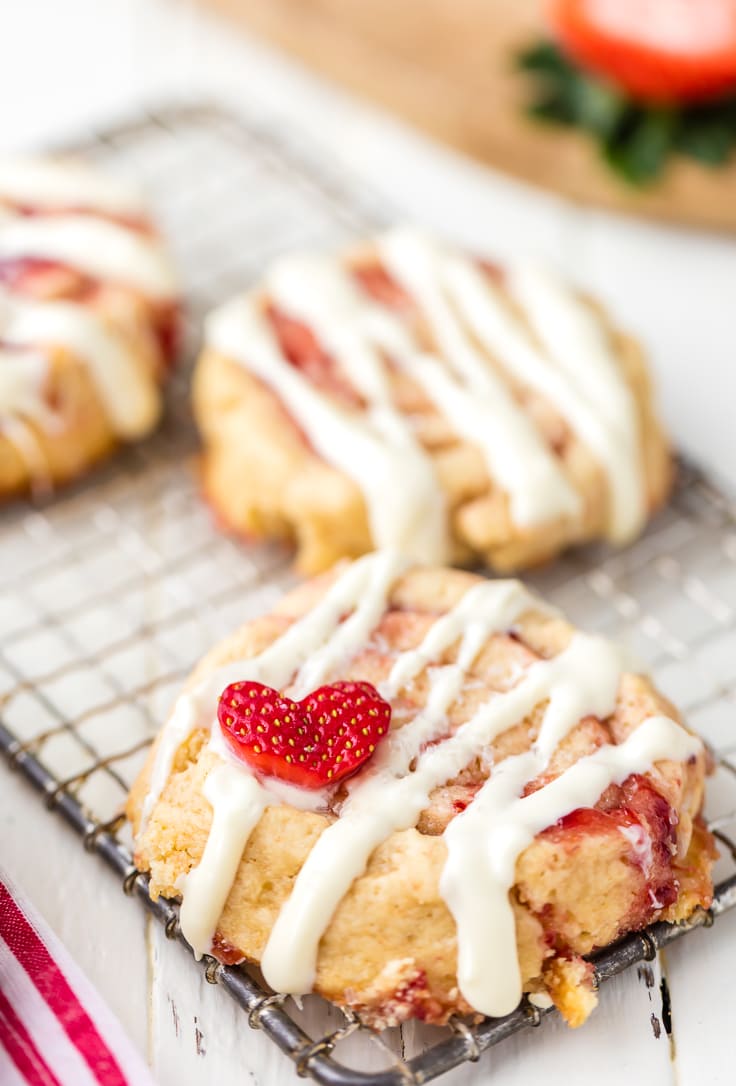 cinnamon roll cookies topped with icing and strawberry hearts