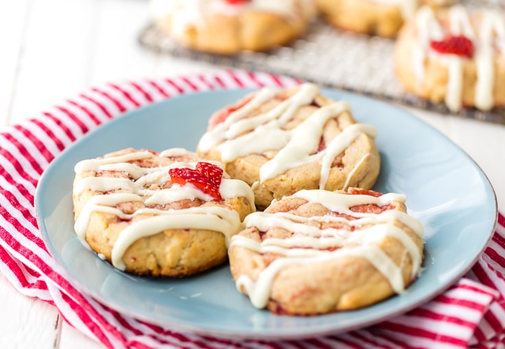 a blue plate with three strawberry cinnamon roll cookies