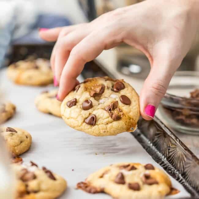 hand holding cookie up from cookie tray