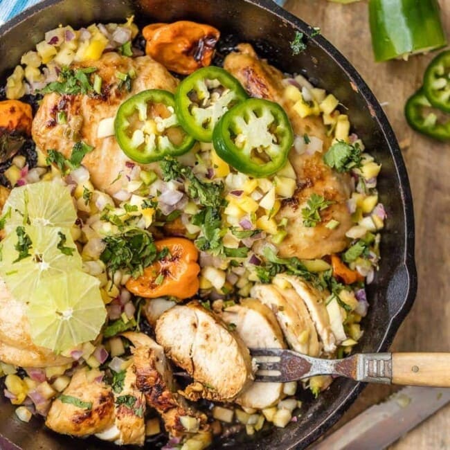 jerk chicken in a skillet with a fork