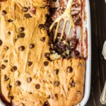 banana split dump cake in a baking dish with spatula