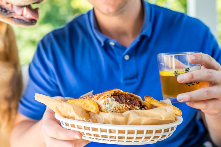 man holding a basket with beef burrito