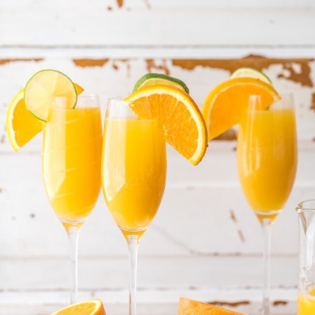 three moscow mule mimosas on a table with sliced oranges