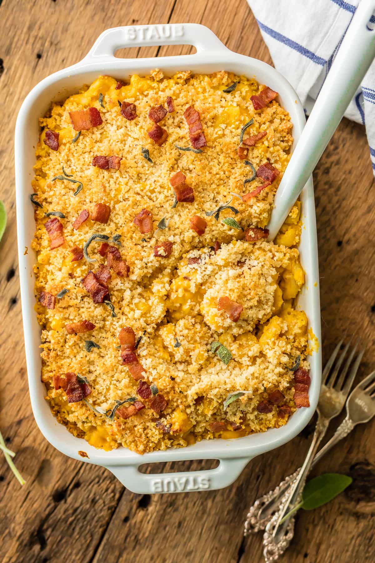 Pumpkin mac and cheese topped with bacon, in a white casserole dish.