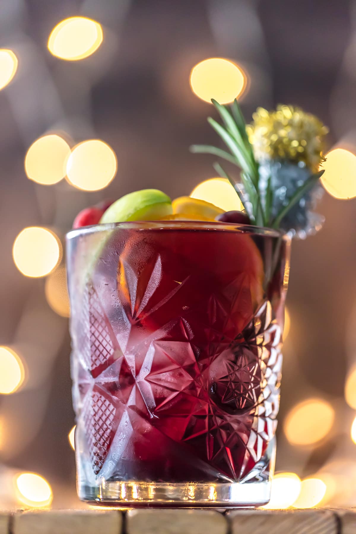 A glass of holiday sangria garnished with rosemary and fruit