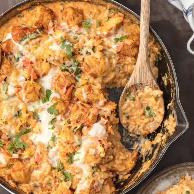 SKILLET CHICKEN CON QUESO is the ultimate one pot meal! Cheesy rice loaded with cilantro, pico de gallo, green chiles, and cream topped with taco spiced chicken. Comfort food has never been easier or cheesier!