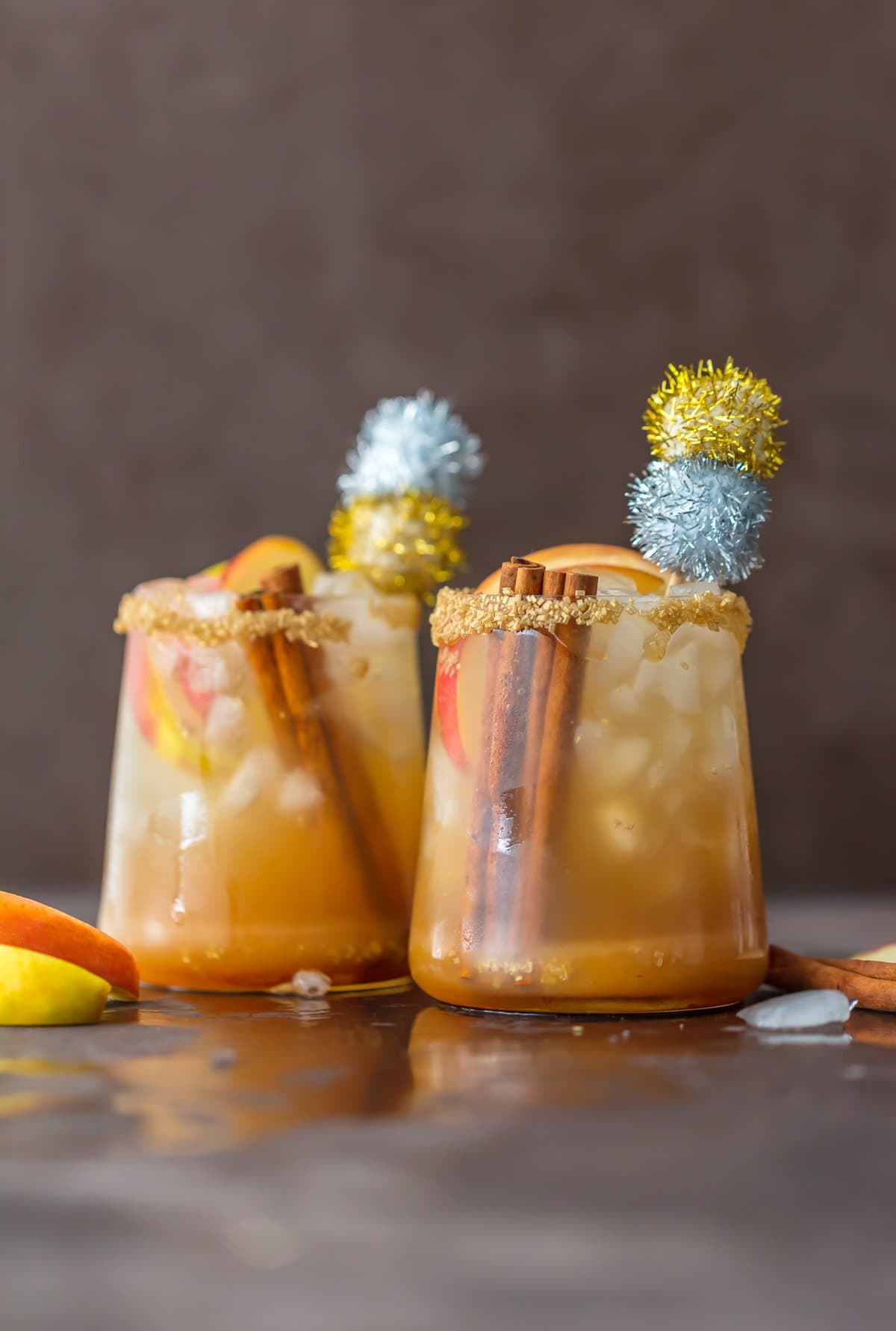 Apple cider cocktail in two glasses garnished with cinnamon sticks and apples