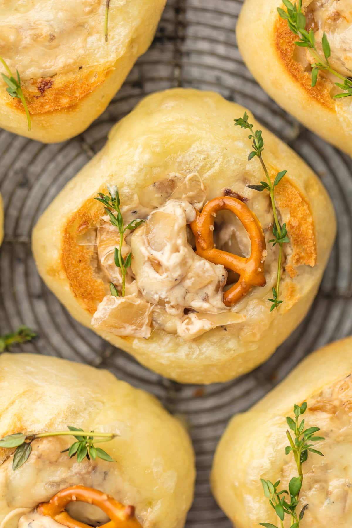 A mini bread bowl filled with french onion dip, with a mini pretzel in the middle