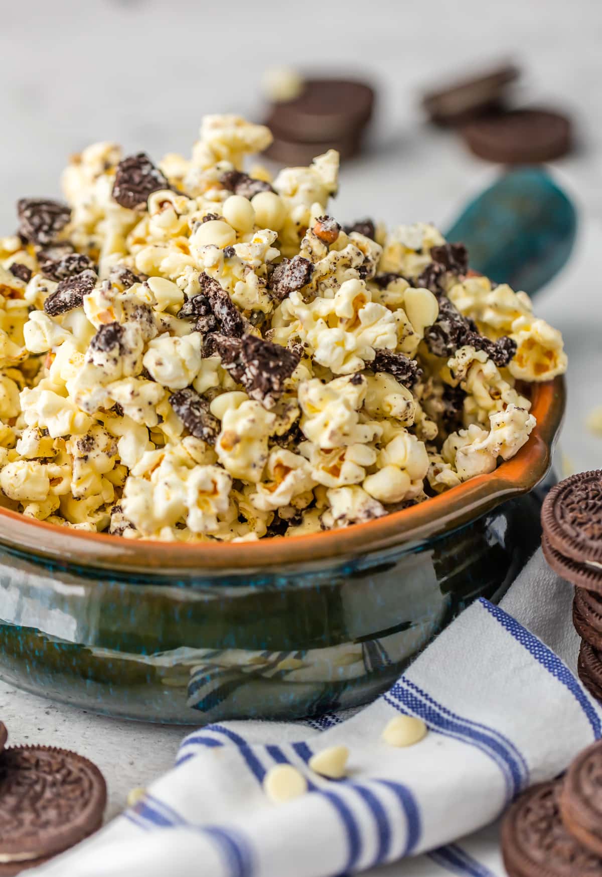 A bowl of Oreo and white chocolate popcorn surrounded by Oreos