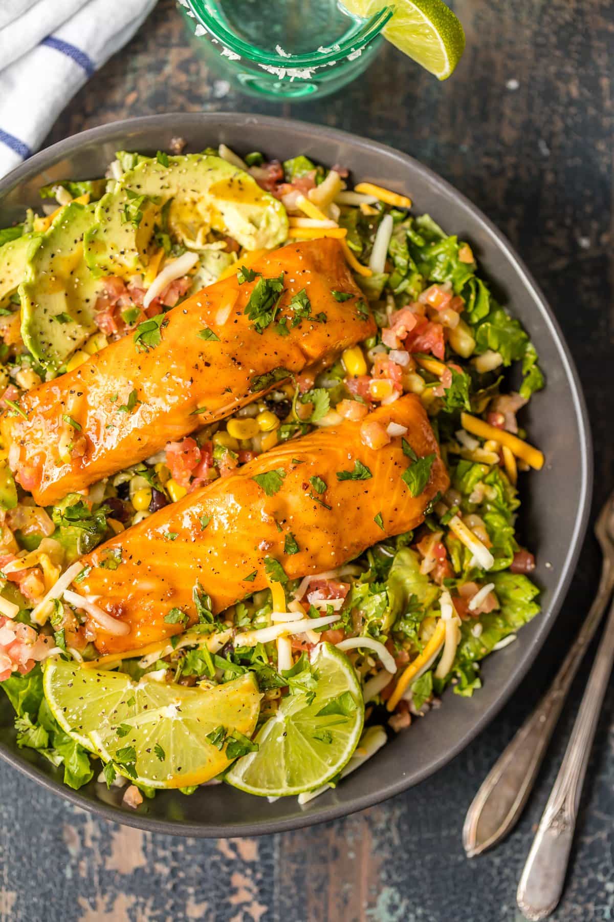 Large salad filled with avocado, lettuce, corn, black beans and topped with tequila lime salmon