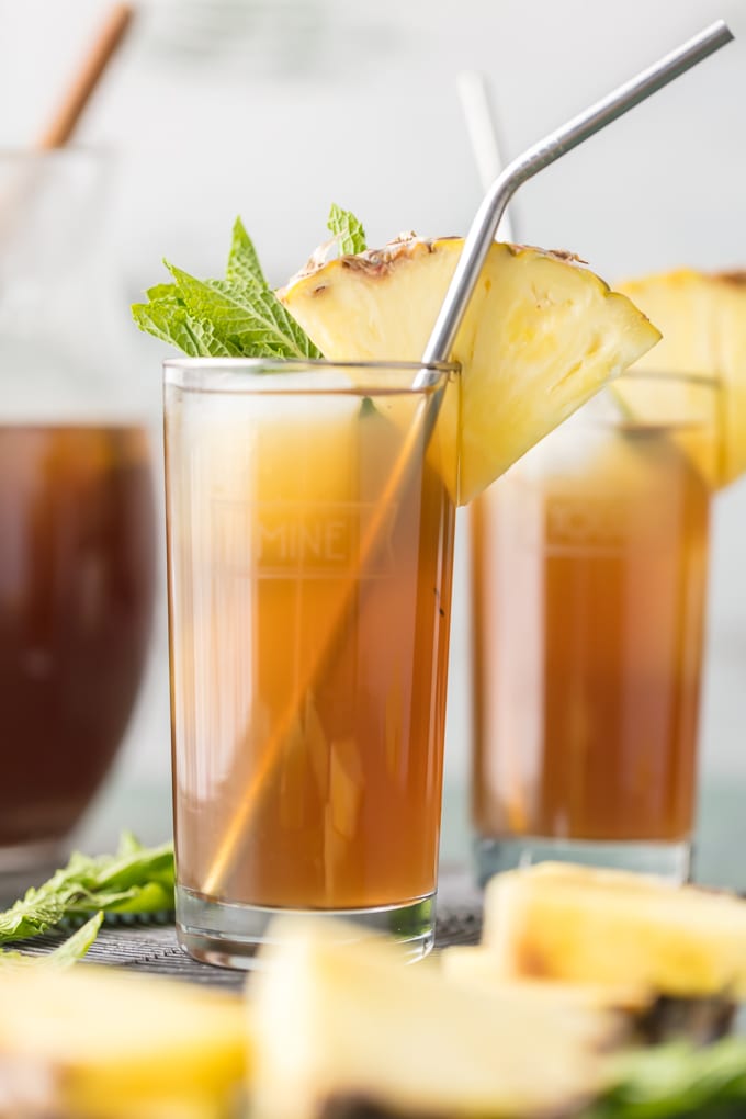 A glass of iced tea with a straw and a pineapple slice