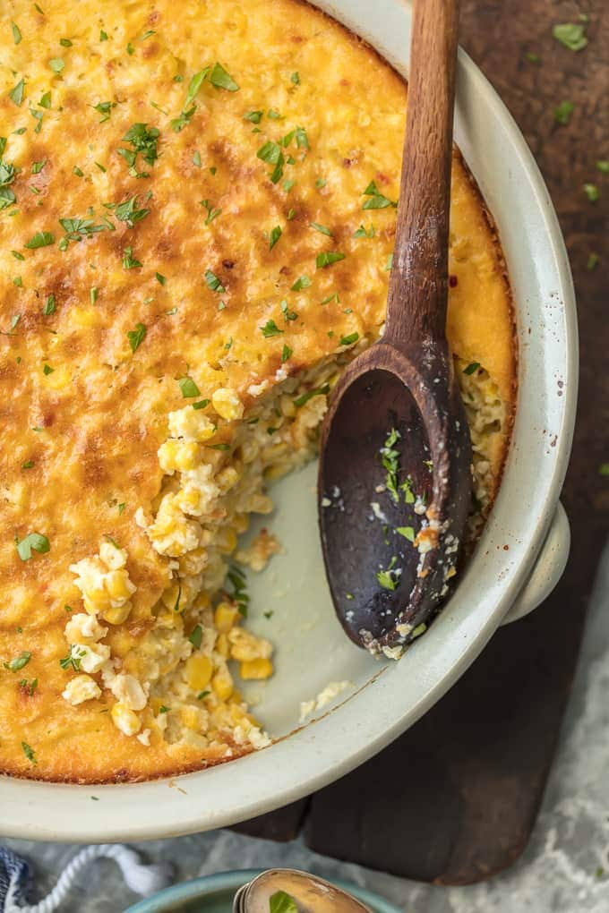 Wooden spoon resting in a partially eaten dish of corn.