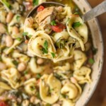 ladle holding tortellini above a bowl