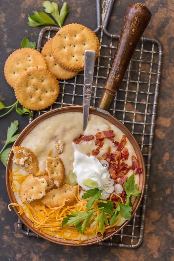 a bowl of baked potato soup topped with bacon, cheese, and crackers