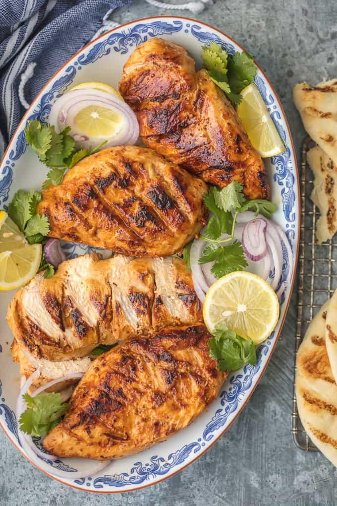 Tandoori Chicken on a platter with sliced limes and onions