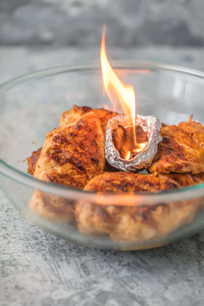 a bowl of chicken with tin foil bowl of smoked chips on fire