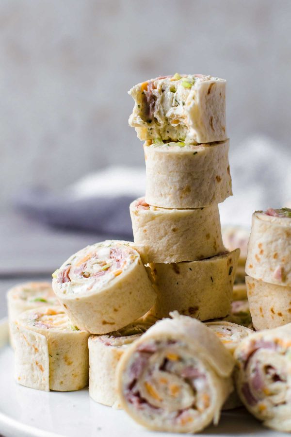 a stack of ham and cheese tortilla pinwheels filled with cream cheese and ranch