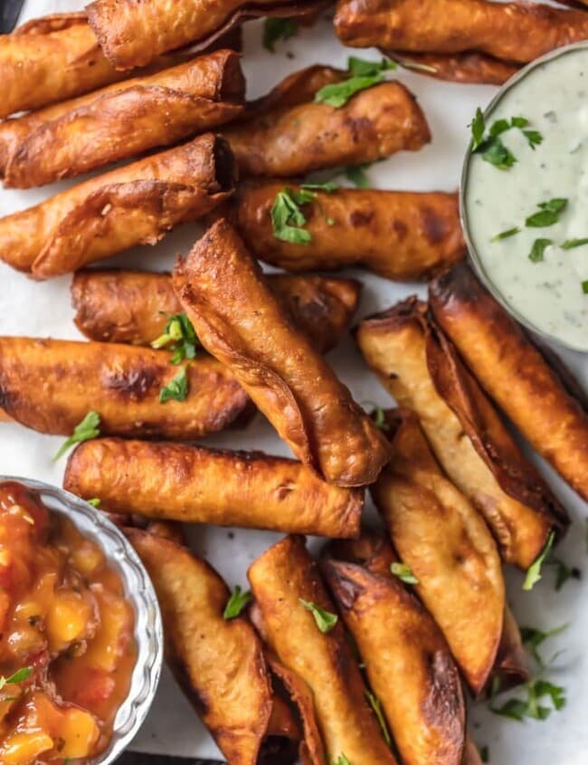 This Taquitos Recipe with Cheese, Beans, and Green Chiles is one of our favorite ways to tailgate. I could eat 50 of these MINI BEAN & CHEESE TAQUITOS! I just can't get enough. Such a fun and easy appetizer for the holidays or game day. This Homemade Taquitos Recipe is always a crowd pleaser.