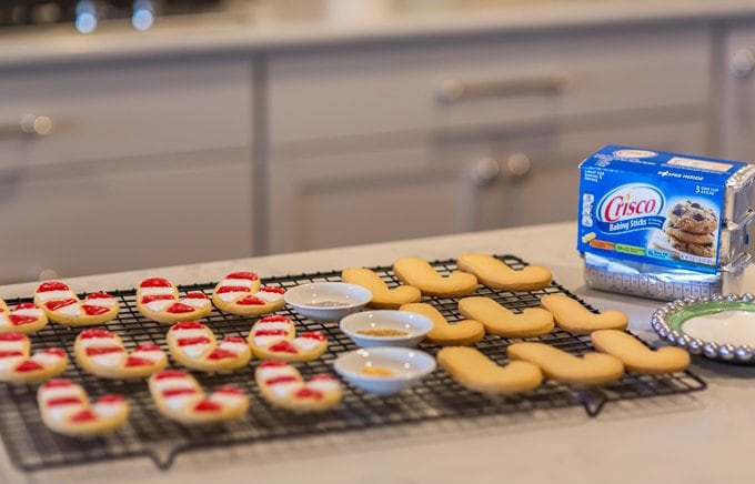 candy cane cut out sugar cookies on a cooling rack. Half are decorated with red and white icing