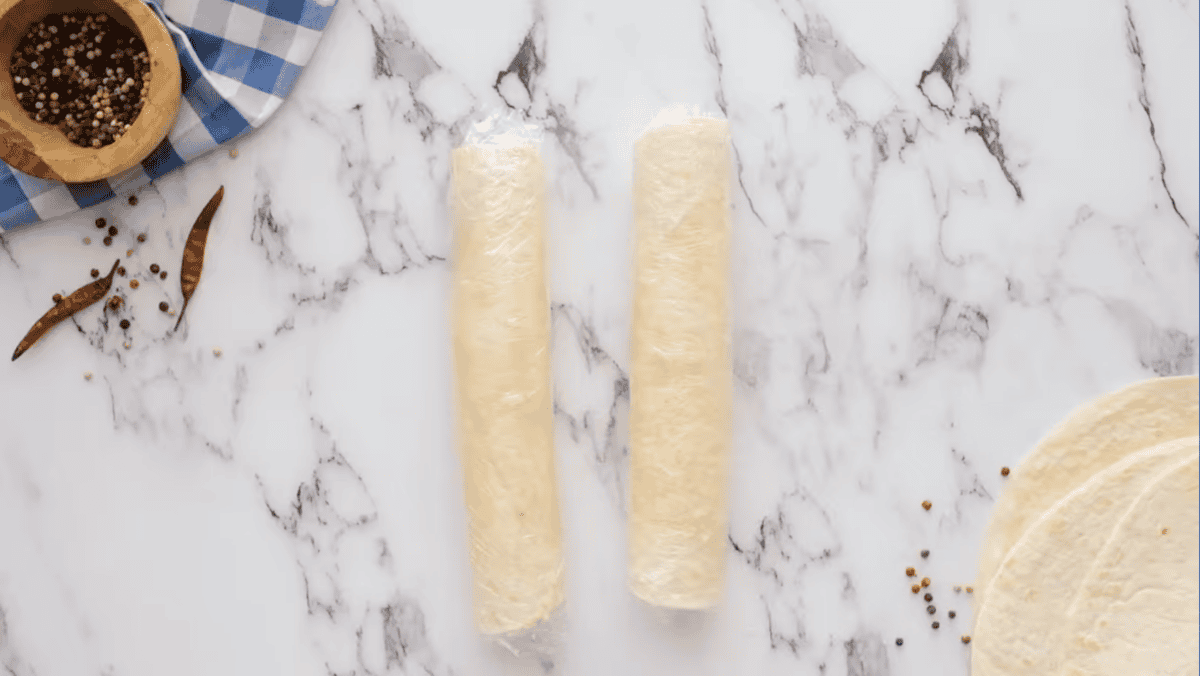 two rolled-up tortillas wrapped in plastic wrap.