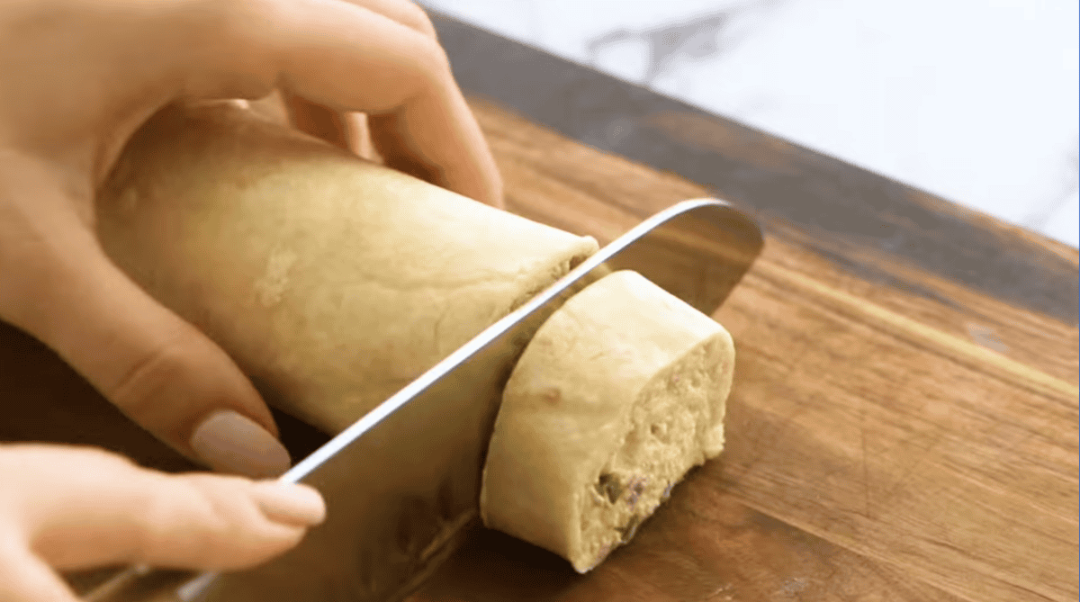 a knife cutting a tortilla roll into small pinwheels.