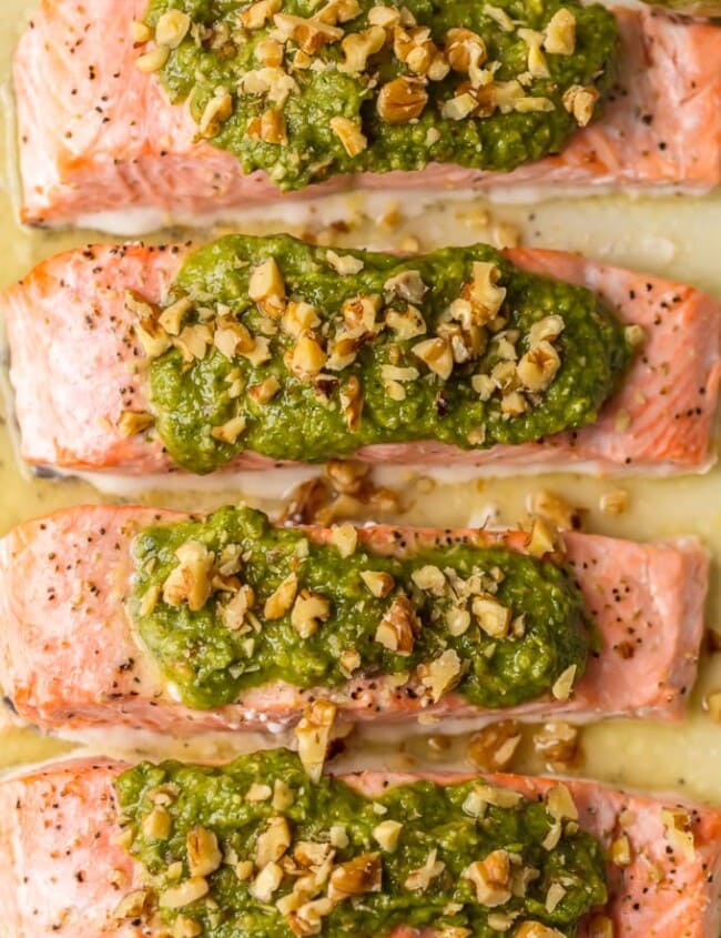 This Baked Pesto Salmon recipe is our favorite simple yet elegant seafood dinner. This Baked Salmon Recipe with Basil Walnut Pesto is bursting with flavor and good fat. The tender flaky salmon is basted in butter, white wine, and lemon juice before baking and then topped with an amazing nutty and rich Basil Walnut Pesto. Best Baked Salmon Recipe ever!