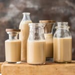 Four jars of homemade Bailey's Irish cream on a wooden cutting board.