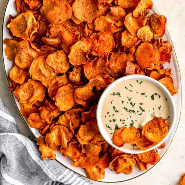 overhead view of baked sweet potato chips on a platter with dipping sauce.